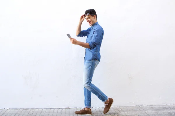 Feliz joven caminando por la calle mirando el teléfono móvil —  Fotos de Stock