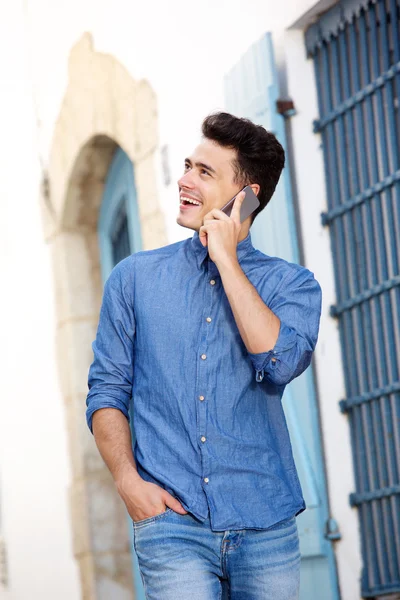 Yürüme ve hareket eden telefon dinleme gülümseyen adam