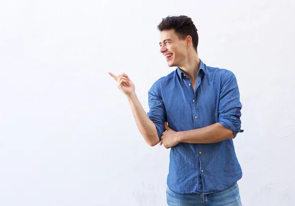 Улыбающийся молодой человек указывает пальцем, чтобы скопировать пространство — стоковое фото