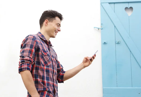 Lachende jonge man lopen buiten met mobiele telefoon — Stockfoto