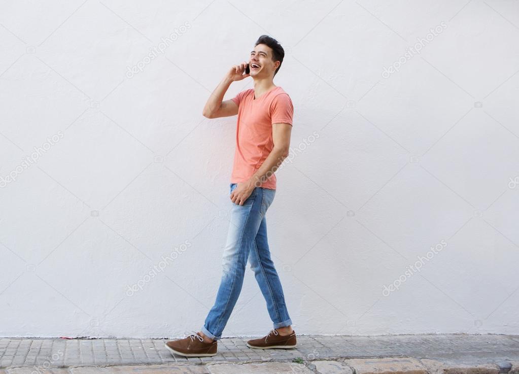 Smiling man walking and listening to mobile phone 