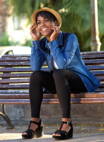 Sonriente joven sentada en el banco del parque —  Fotos de Stock