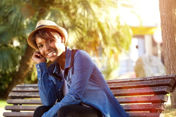 Lächelnde junge afrikanisch-amerikanische Frau sitzt draußen — Stockfoto