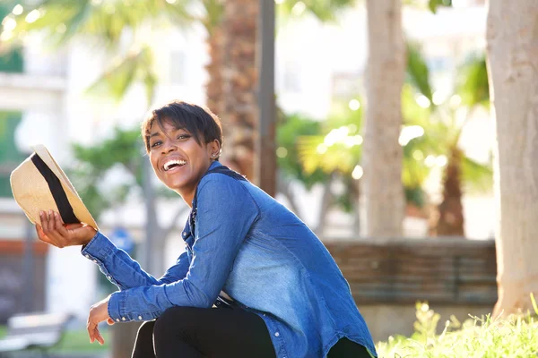 Jonge zwarte vrouw lachen buiten met hoed — Stockfoto