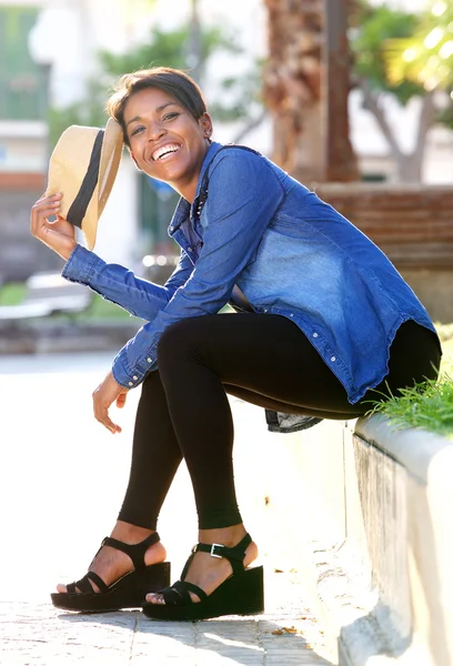 Sorrindo jovem afro-americana sentada fora — Fotografia de Stock