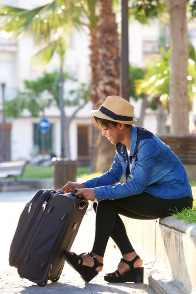 Gyönyörű fekete nő ül kívül bőrönd — Stock Fotó