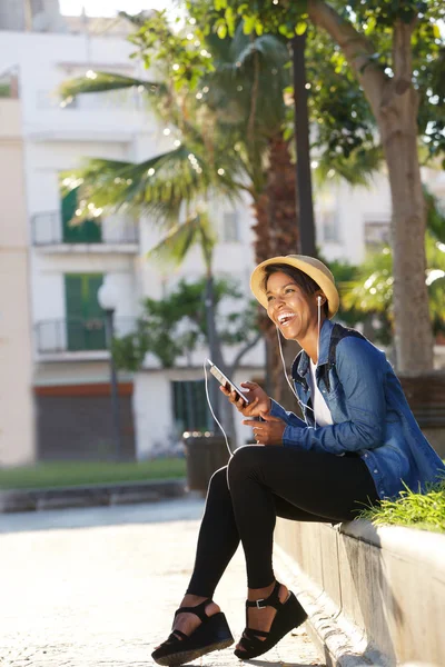 Giovane donna nera che ride e ascolta musica sul cellulare — Foto Stock