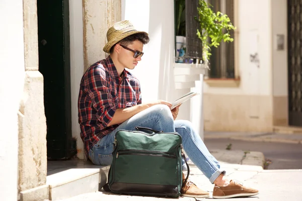 Viajando homem sentado na calçada ler mapa — Fotografia de Stock