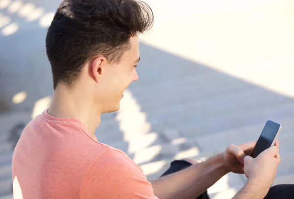 Jonge kerel typen SMS-bericht op mobiele telefoon — Stockfoto