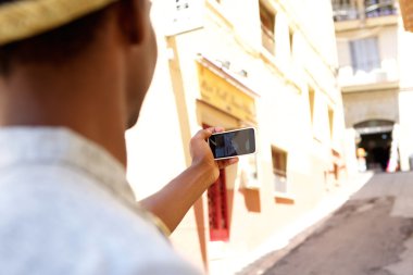 Young man walking in town taking selfie