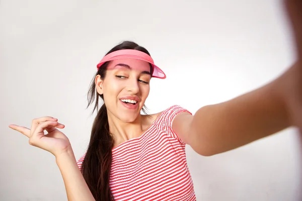 Smiling young woman with pink cap taking selfie — Stock Photo, Image