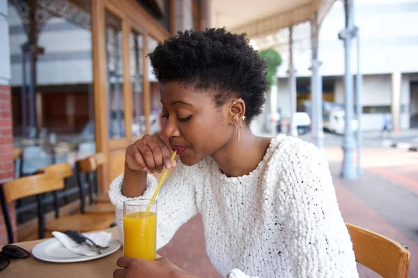 Mujer africana bebiendo jugo de naranja en la cafetería al aire libre — Foto de Stock