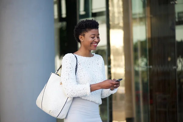 Mujer moderna caminando con teléfono celular en la ciudad —  Fotos de Stock