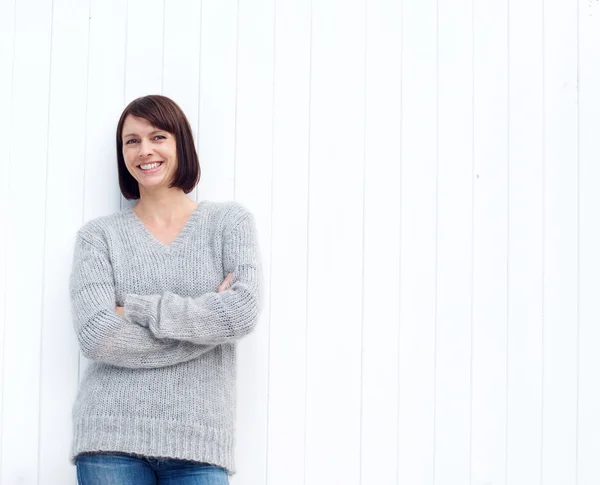 Reife Frau lächelt gegen weiße Wand — Stockfoto