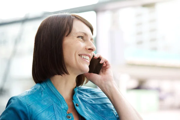 Lachende oudere vrouw met behulp van mobiele telefoon — Stockfoto