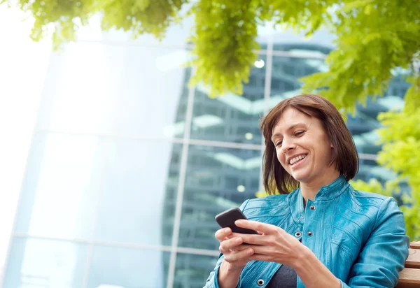 Sorrindo mulher de meia-idade usando telefone celular fora — Fotografia de Stock