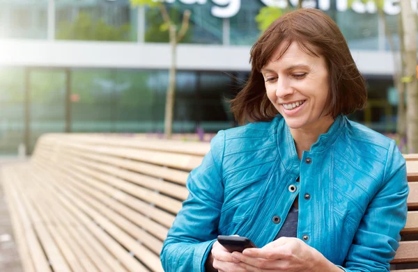 Sonriendo mujer madura utilizando el teléfono móvil fuera —  Fotos de Stock