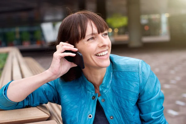 Kobieta uśmiechając się i słuchanie muzyki do telefonów komórkowych — Zdjęcie stockowe