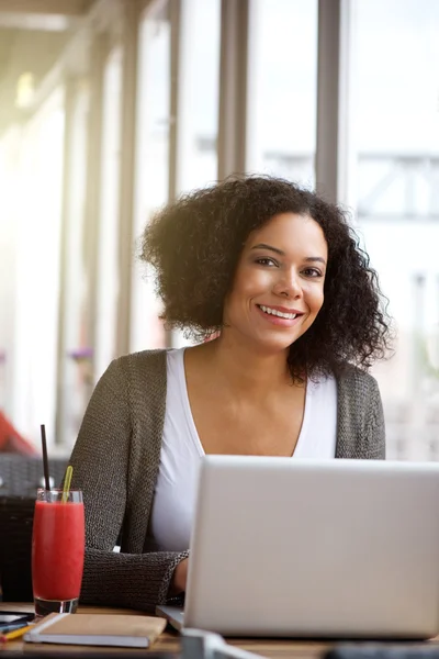 Uśmiechający się african american kobieta korzysta z laptopa w kawiarni — Zdjęcie stockowe