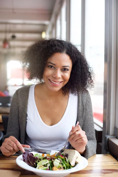 Smiling black woman eating salad at restaurant — Stock Photo, Image