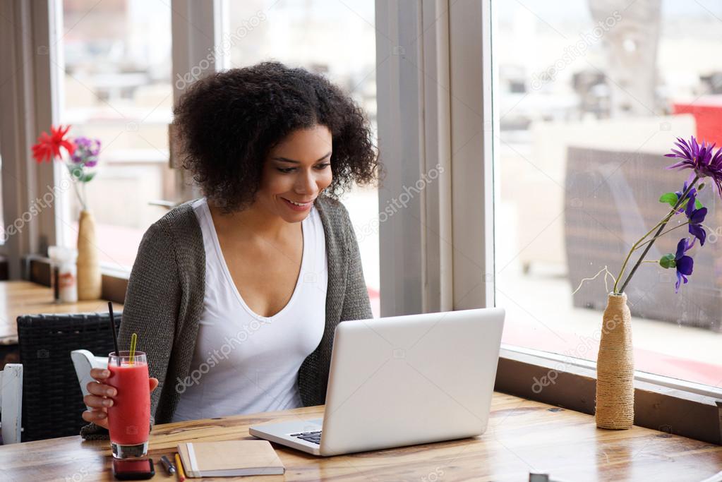 Smiling african american woman using laptop at cafe