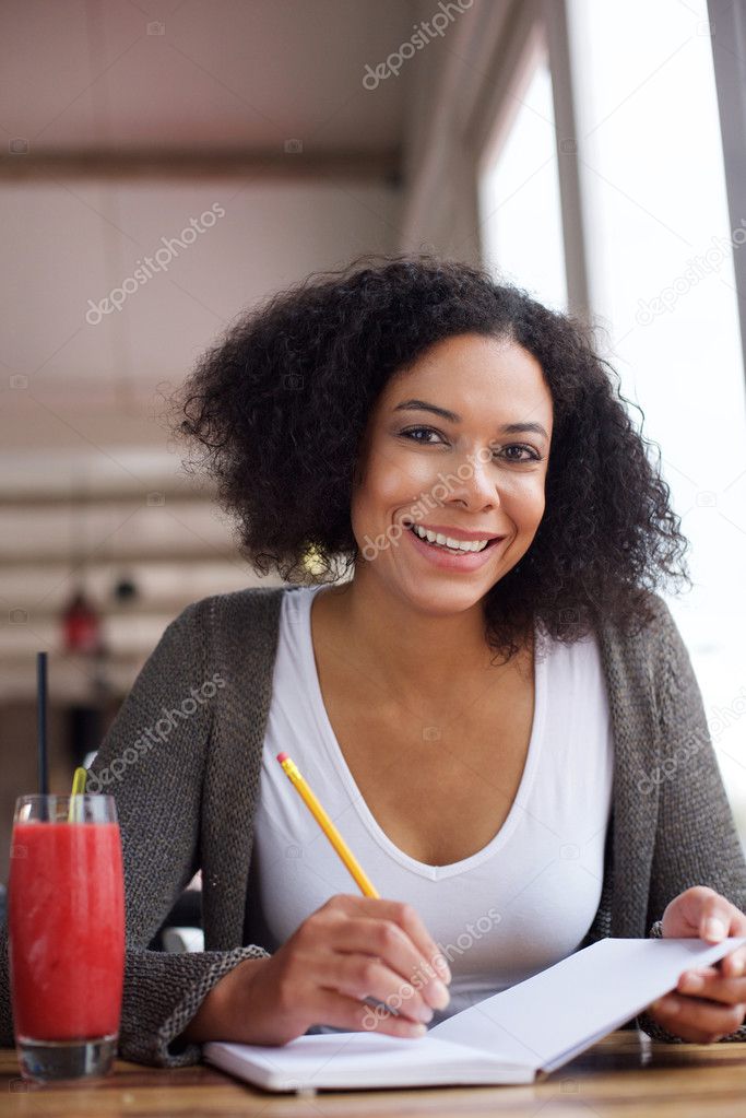 Smiling african american female student writing in book