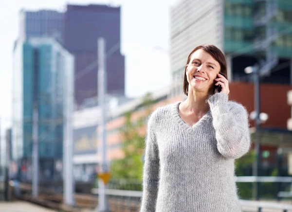 Uśmiechający się kobiety stojącej w mieście z telefonu komórkowego — Zdjęcie stockowe