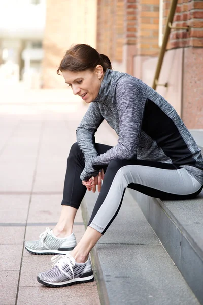 Sportliche Frau sitzt nach dem Training ausgeruht draußen — Stockfoto