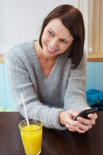 Smiling woman sitting at cafe with cell phone — Stock Photo, Image