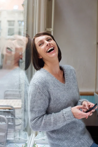 Vrouw lachen met mobiele telefoon thuis — Stockfoto