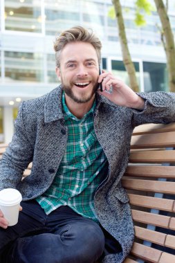 Yakışıklı adam gülüyor ve cep telefonu dışında dinlerken