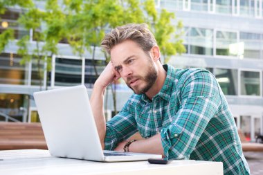 Dışarıda laptop ile şehirde oturan adam