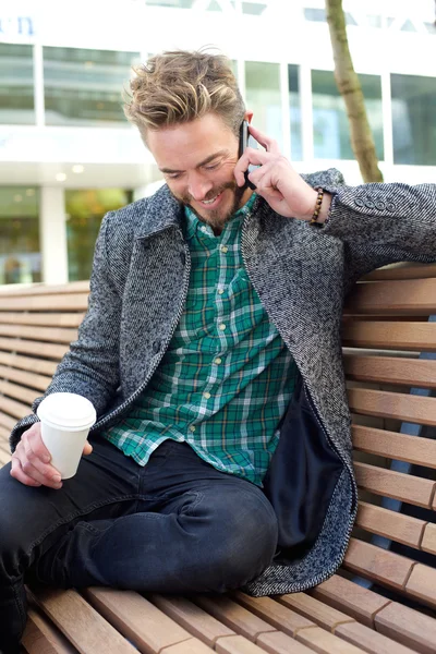 Muž sedí a mluví na mobilním telefonu — Stock fotografie