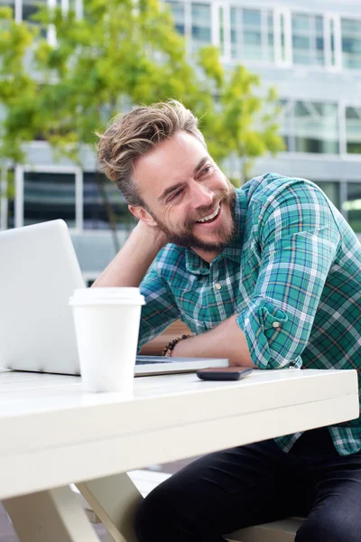 Bonito homem sorrindo lá fora com laptop — Fotografia de Stock