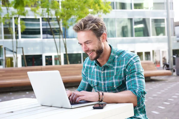 Uomo sorridente che lavora su laptop all'aperto — Foto Stock