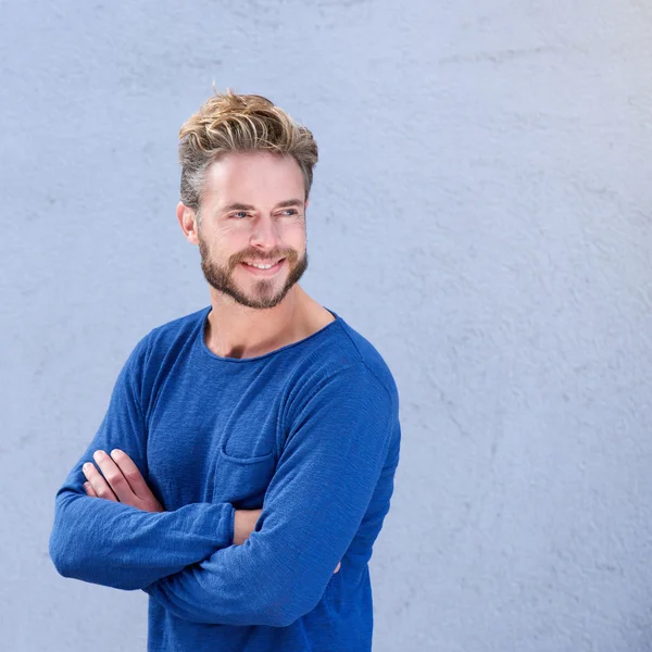 Homme souriant avec les bras croisés sur fond gris — Photo