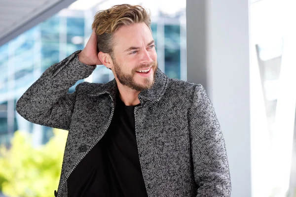 Handsome man smiling with hand in hair — Stock Photo, Image