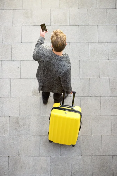 Путешествующий мужчина ходит с чемоданом для рекламы мобильного телефона — стоковое фото
