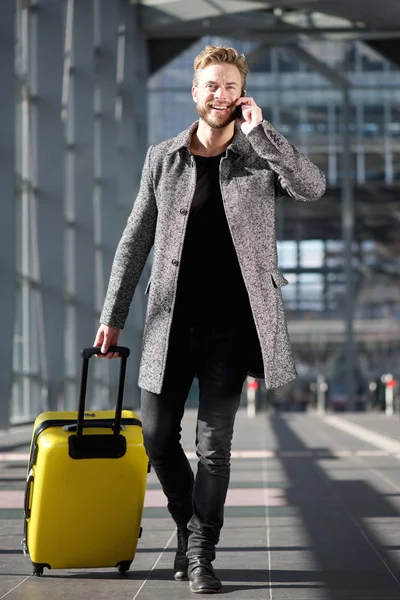Smiling travel man walking with mobile phone and suitcase — Stock Photo, Image