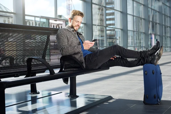 Pohledný muž relaxační na letišti s mobilním telefonem — Stock fotografie