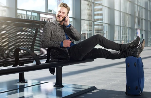 Cool travel man relaxing at airport with cellphone — Stock Photo, Image