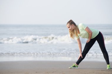 Sahilde uzanan aşağı sportif genç kadın bend
