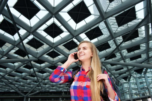 Uśmiechnięta młoda kobieta z plecaka i telefon komórkowy — Zdjęcie stockowe