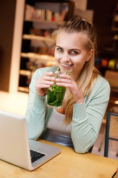 Jeune femme souriant avec boisson et ordinateur portable au café — Photo