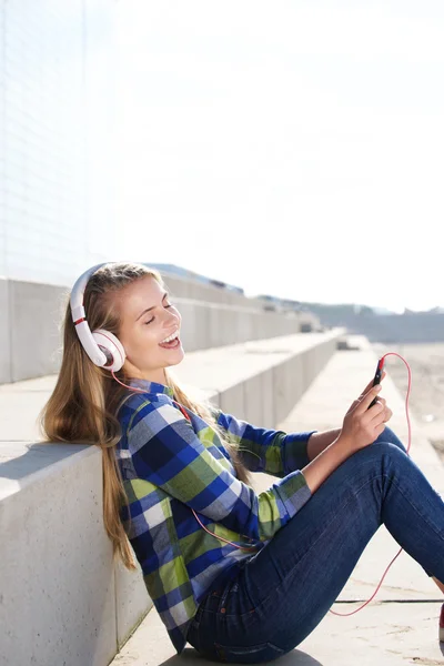 Jeune femme souriante écoutant de la musique avec un téléphone intelligent — Photo