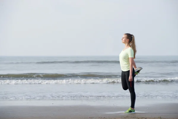 Sportig ung kvinna stretching motion på stranden — Stockfoto