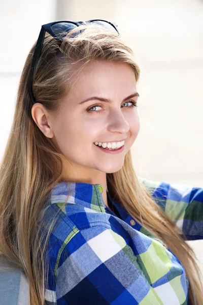 Lächelnde junge blonde Frau sitzt draußen Stockbild
