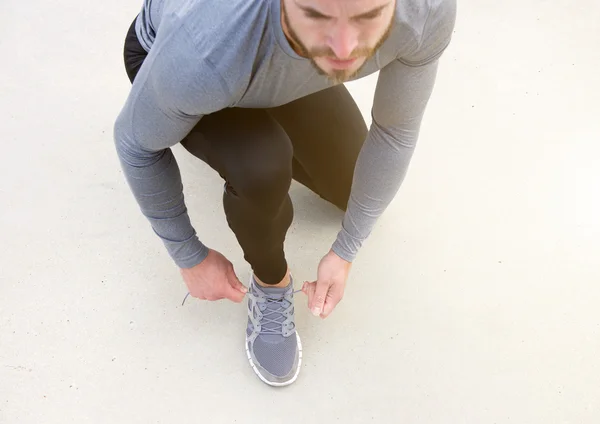 Hombre atando zapato deportivo de cordones — Foto de Stock