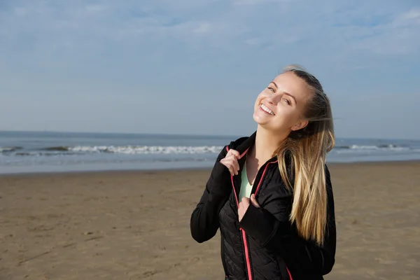 Usmívající se dívka fitness stojí venku na pláži — Stock fotografie