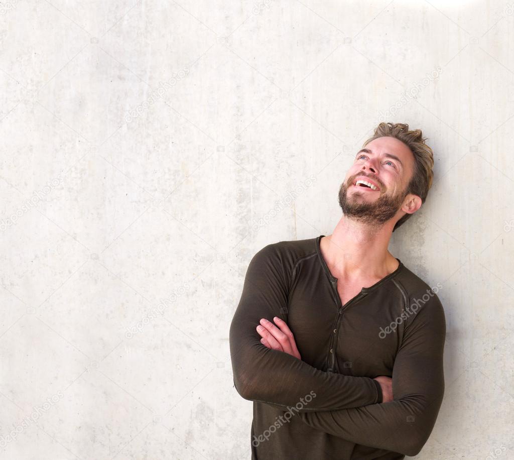 Laughing handsome man with arms crossed looking up